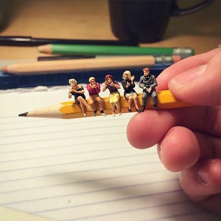 Miniature figures sitting on a pencil
