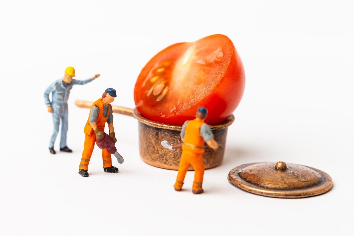 Miniatuur-koks werken aan een grote tomaat