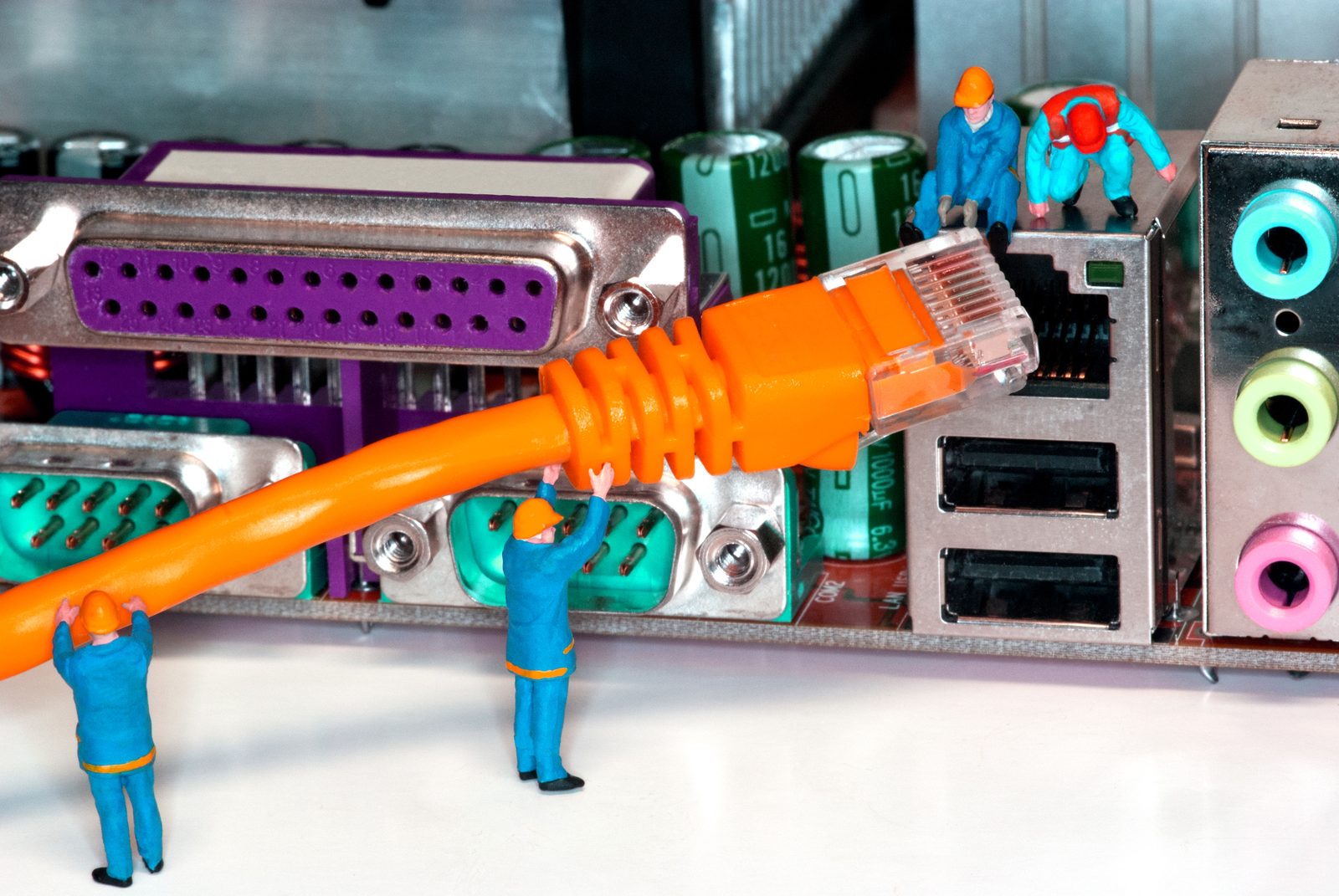 Miniatuur-technici bij een netwerkkabel en moederbord