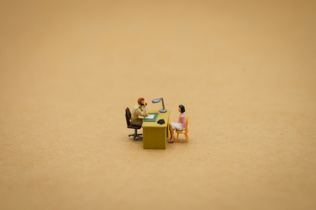 Miniatuurfiguur alleen aan een bureau