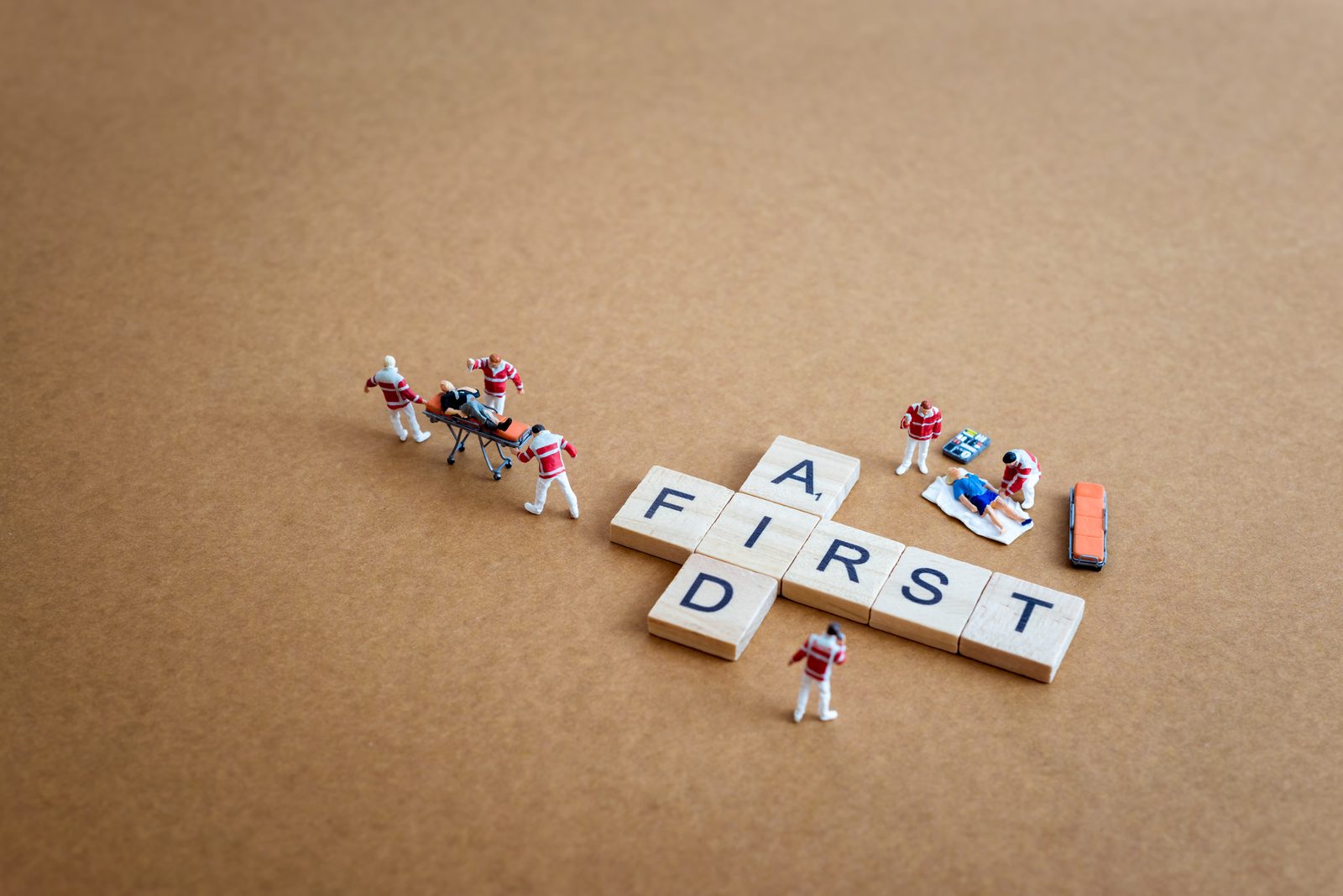 Letter blocks spelling First Aid with miniature figures