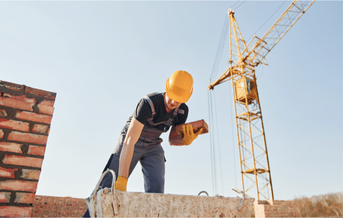 Metselaar aan het werk met bouwkraan op de achtergrond